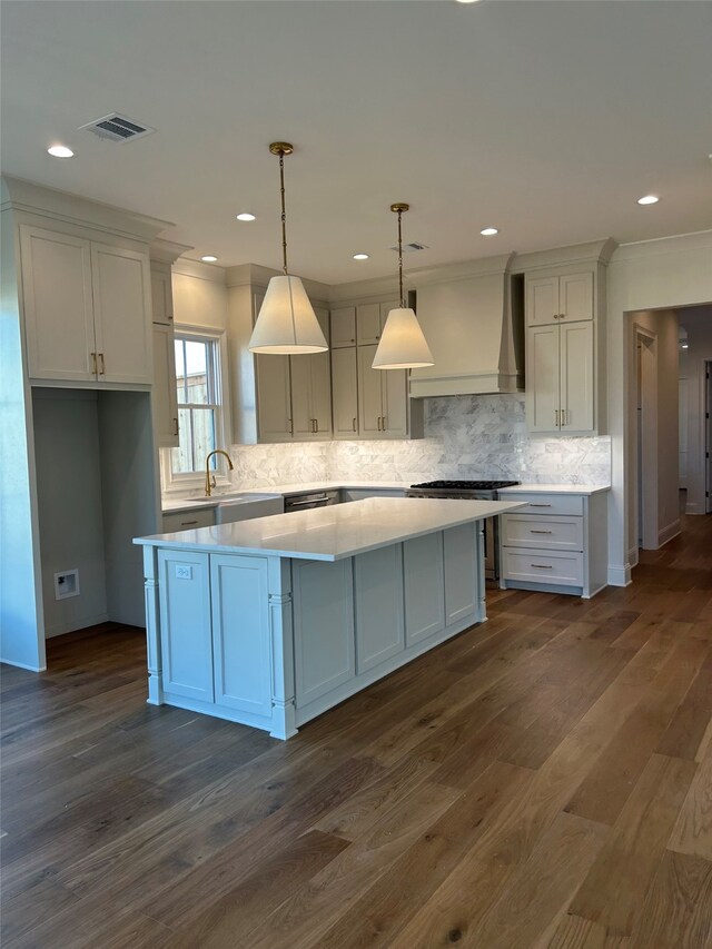 kitchen with stainless steel microwave, white cabinetry, ornamental molding, and decorative light fixtures