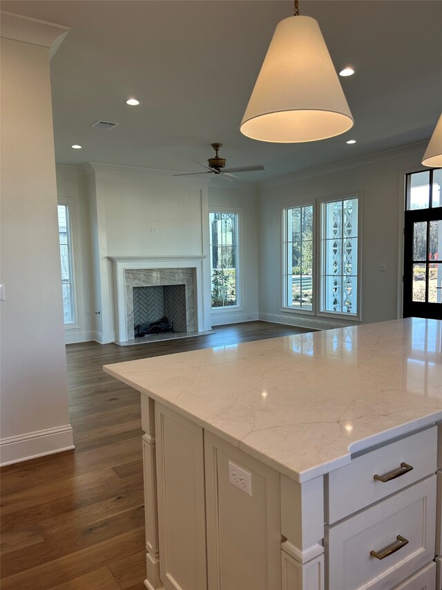 unfurnished living room featuring dark wood-type flooring, a fireplace, ornamental molding, and ceiling fan with notable chandelier