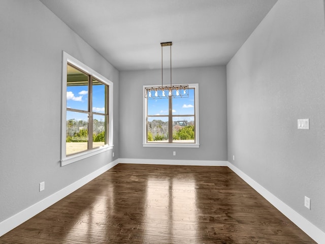 unfurnished dining area featuring a chandelier and dark hardwood / wood-style floors