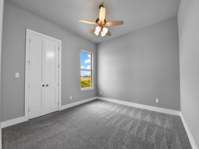 unfurnished room featuring ceiling fan and dark colored carpet