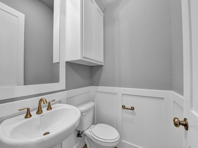 170 Fan Mill Trl, Weatherford, TX 76085 - half bath featuring wainscoting, a textured wall, a decorative wall, toilet, and a sink