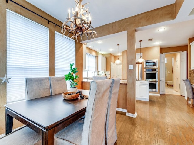 dining space with light hardwood / wood-style floors and a chandelier