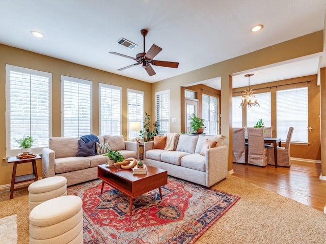 living room with ceiling fan with notable chandelier and hardwood / wood-style flooring