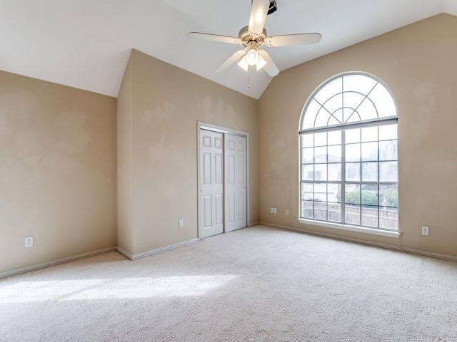 unfurnished bedroom featuring ceiling fan, vaulted ceiling, light carpet, and a closet