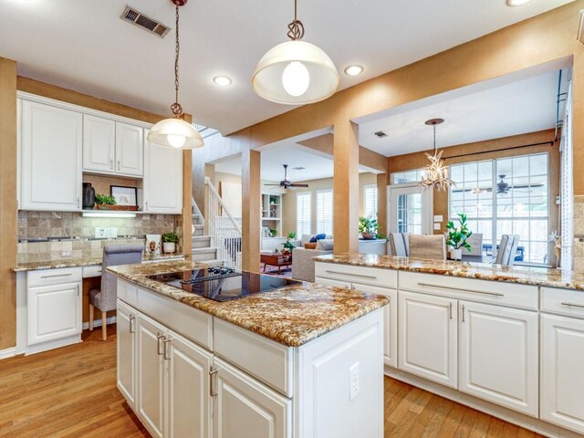 kitchen with white cabinets, a center island, backsplash, hanging light fixtures, and appliances with stainless steel finishes