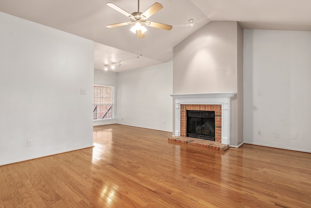 unfurnished living room featuring a brick fireplace, ceiling fan, lofted ceiling, and light hardwood / wood-style flooring