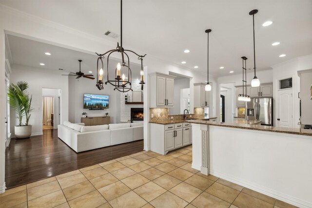 kitchen with dark stone countertops, decorative backsplash, white cabinets, stainless steel fridge with ice dispenser, and decorative light fixtures