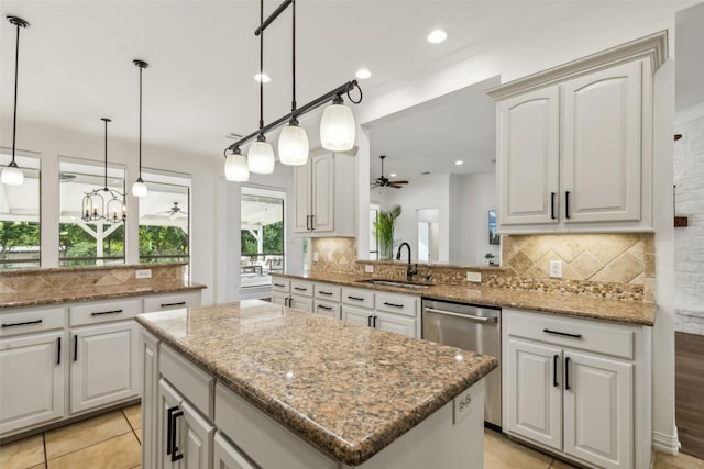 kitchen featuring kitchen peninsula, white cabinetry, sink, and a kitchen island