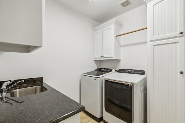 laundry room with washer and clothes dryer, cabinets, light tile patterned floors, and sink