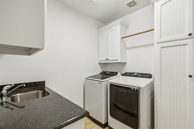 clothes washing area with cabinets, light tile patterned flooring, sink, and washing machine and clothes dryer