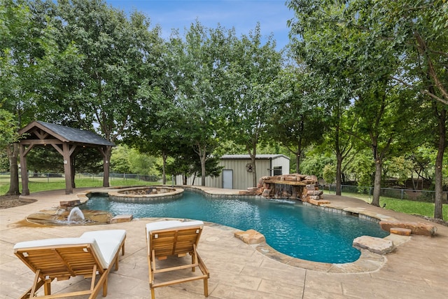 view of pool with an in ground hot tub, an outbuilding, pool water feature, a gazebo, and a patio