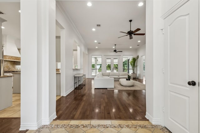 unfurnished living room featuring ceiling fan, light tile patterned flooring, crown molding, and french doors