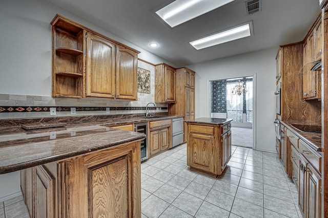 kitchen featuring dark stone counters, sink, appliances with stainless steel finishes, a kitchen island, and beverage cooler