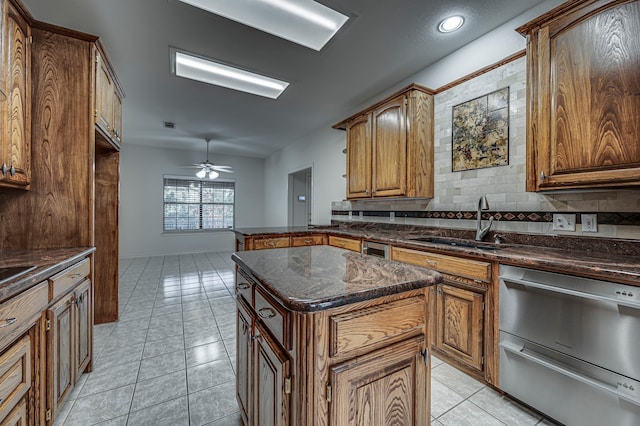 kitchen featuring a center island, backsplash, sink, ceiling fan, and light tile patterned flooring