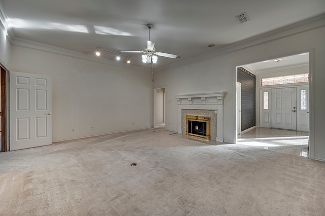 unfurnished living room featuring a high end fireplace, light colored carpet, ceiling fan, and crown molding