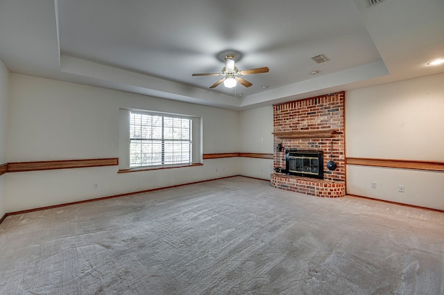 unfurnished living room with a raised ceiling, ceiling fan, and light carpet