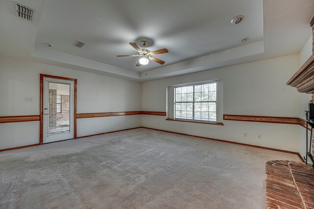 carpeted empty room with a raised ceiling and ceiling fan