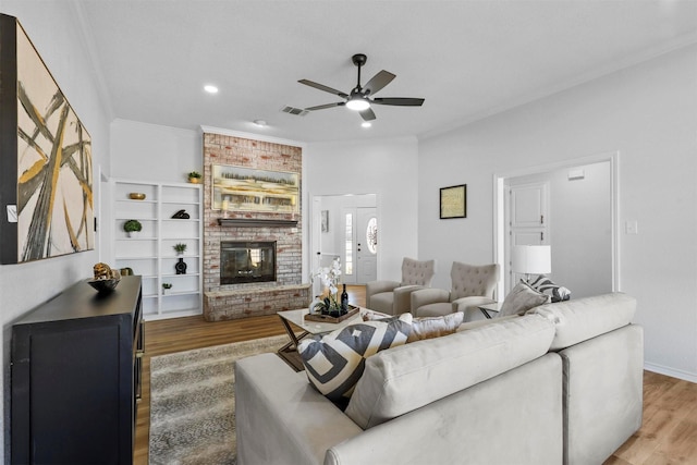 living room featuring hardwood / wood-style flooring, ceiling fan, a fireplace, and crown molding