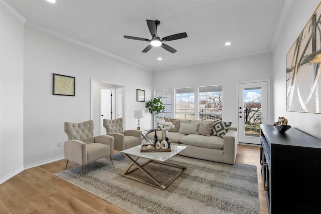 living room with a textured ceiling, hardwood / wood-style flooring, ceiling fan, and crown molding