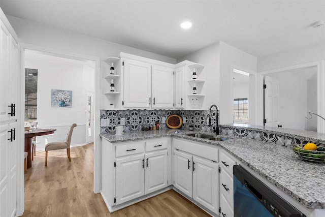 kitchen featuring white cabinets, sink, light hardwood / wood-style flooring, light stone countertops, and dishwashing machine