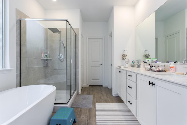 bathroom featuring plus walk in shower, wood-type flooring, and vanity