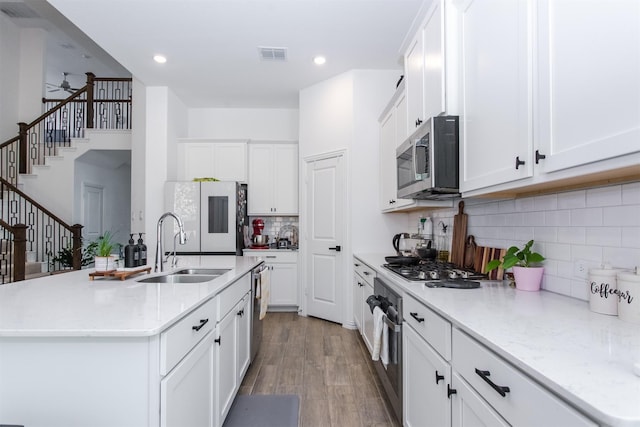 kitchen with white cabinetry, a kitchen island with sink, sink, and appliances with stainless steel finishes