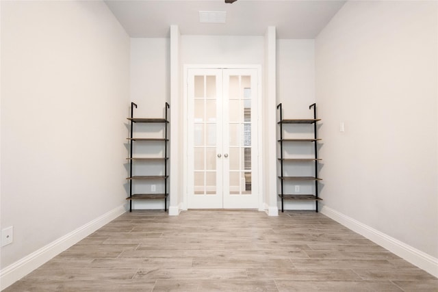 empty room with light hardwood / wood-style floors and french doors