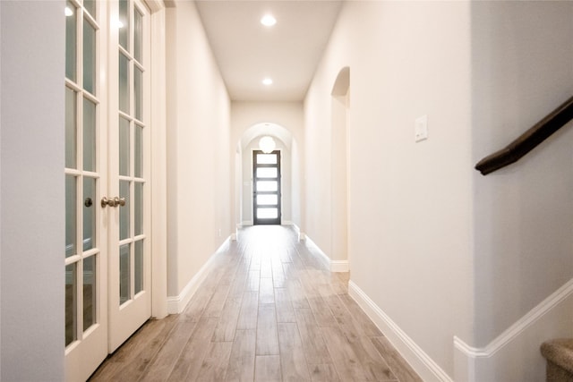 hallway with light hardwood / wood-style floors and french doors