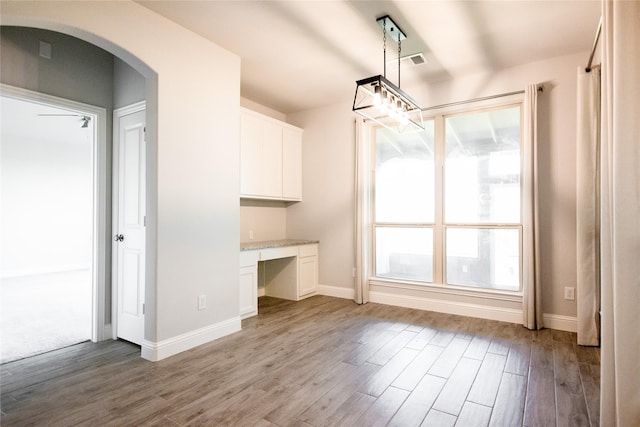 unfurnished dining area featuring built in desk and light hardwood / wood-style flooring