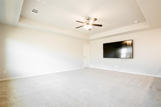 carpeted empty room featuring a tray ceiling and ceiling fan