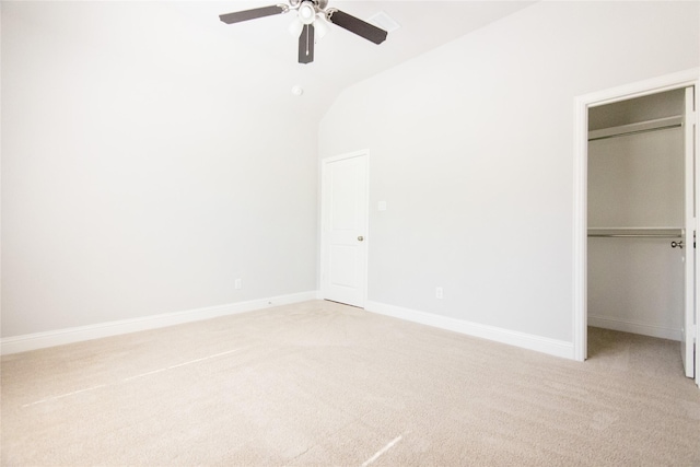 unfurnished bedroom featuring a walk in closet, lofted ceiling, a closet, and light carpet