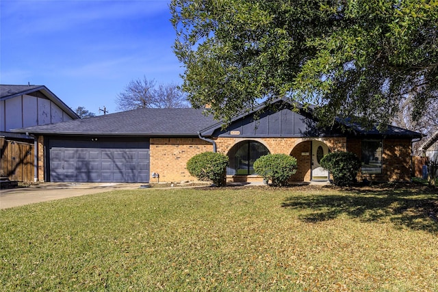 view of front of home with driveway, roof with shingles, an attached garage, a front yard, and brick siding