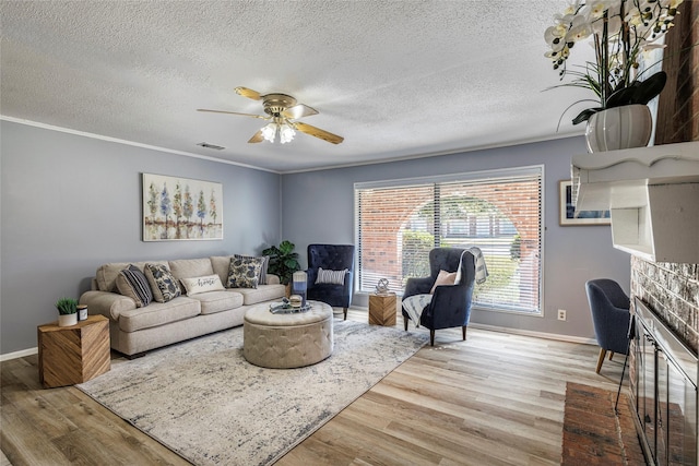 living area with ceiling fan, wood finished floors, visible vents, and crown molding