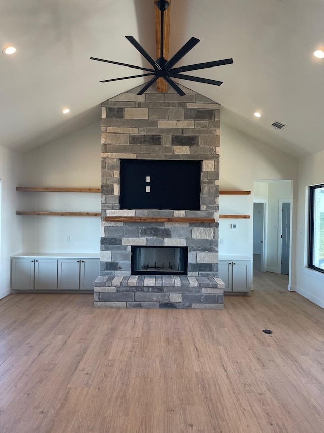 unfurnished living room with ceiling fan, a fireplace, vaulted ceiling, and light hardwood / wood-style flooring