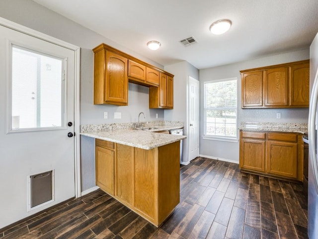 kitchen with light stone countertops, kitchen peninsula, and sink