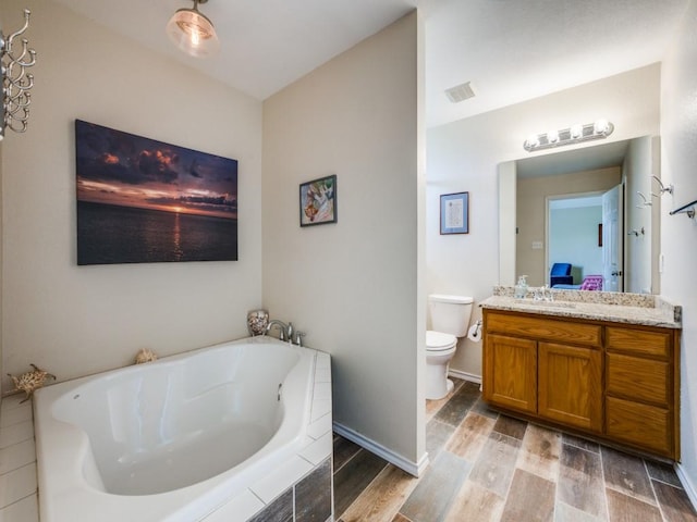 bathroom with vanity, toilet, and tiled tub