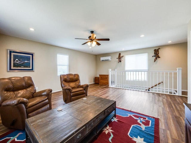 living room with an AC wall unit, ceiling fan, and hardwood / wood-style flooring