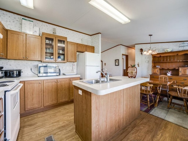 kitchen with pendant lighting, white appliances, an inviting chandelier, crown molding, and light wood-type flooring