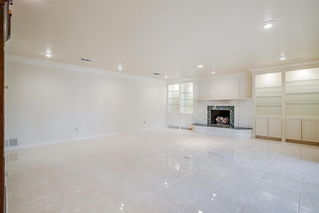 unfurnished living room featuring built in shelves, ornamental molding, a fireplace, and light tile patterned floors