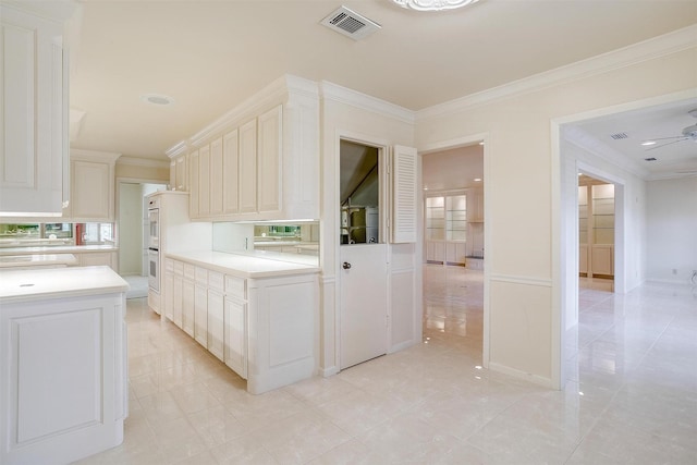 kitchen featuring ceiling fan, ornamental molding, and white cabinets