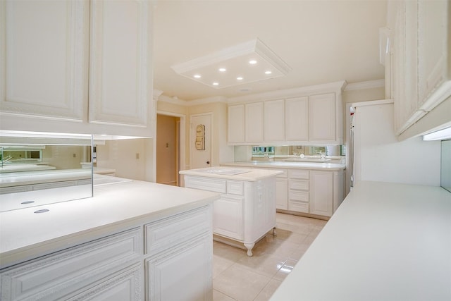 kitchen featuring white cabinetry, a center island, light tile patterned flooring, and crown molding