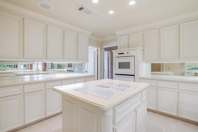 kitchen with crown molding, white appliances, a center island, and light tile patterned floors