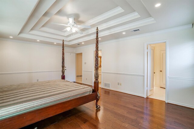 bedroom featuring hardwood / wood-style floors, ornamental molding, and a raised ceiling