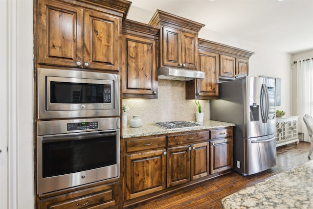 kitchen with backsplash, light stone counters, dark hardwood / wood-style flooring, and appliances with stainless steel finishes