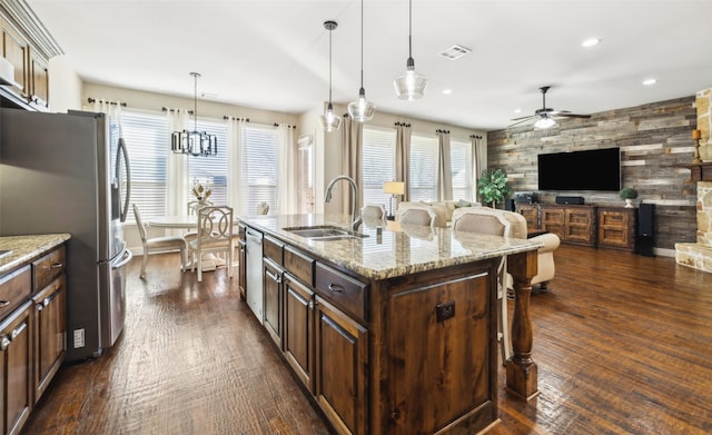 kitchen featuring light stone countertops, sink, pendant lighting, a kitchen island with sink, and ceiling fan with notable chandelier