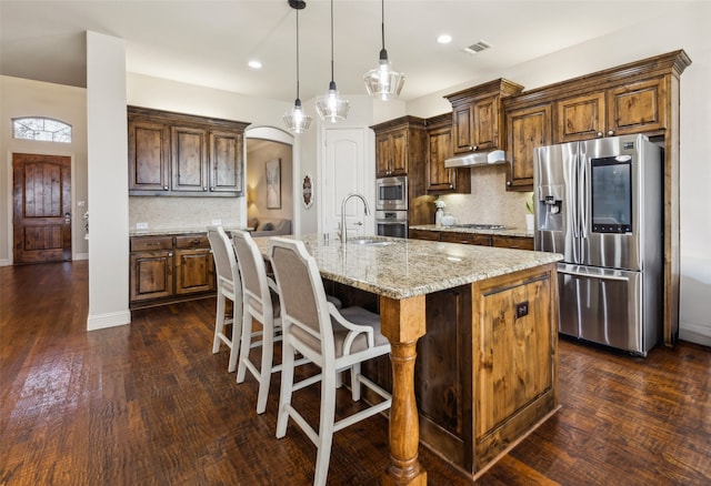 kitchen with tasteful backsplash, sink, an island with sink, and appliances with stainless steel finishes