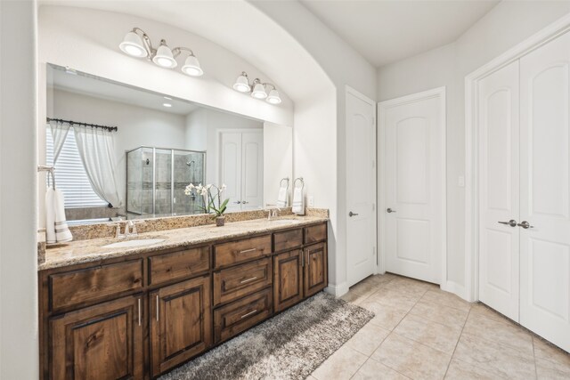 bathroom with a shower with door, vanity, and tile patterned flooring