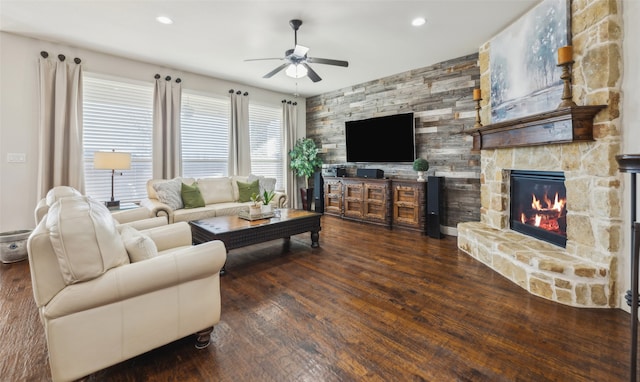 living room featuring a fireplace, ceiling fan, and dark wood-type flooring