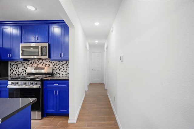 kitchen with stainless steel appliances, blue cabinetry, dark stone countertops, and tasteful backsplash