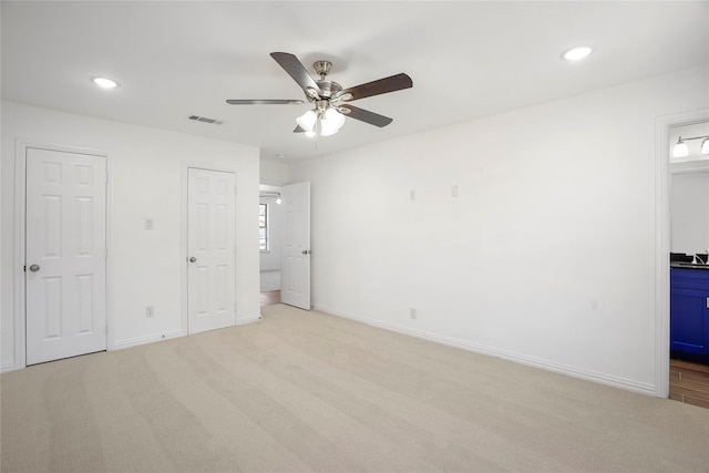 unfurnished bedroom with connected bathroom, ceiling fan, and light colored carpet